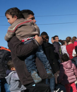 Un homme porte un enfant dans ses bras, ce sont des réfugiés qui attendent le train pour continuer leur voyage en Europe occidentale à la frontière entre Macédoine et Grèce, en dehors du village Gevgelija en République de Macédoine, anciennement Yougoslavie.